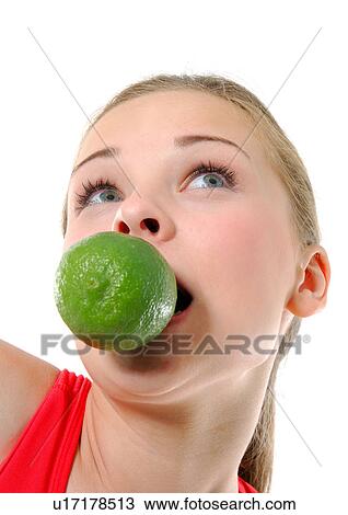 Stock Image - Close-up of a young woman biting a lime on her mouth. Fotosearch