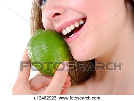 Stock Image - Close-up of a young woman holding a lime and smiling. Fotosearch