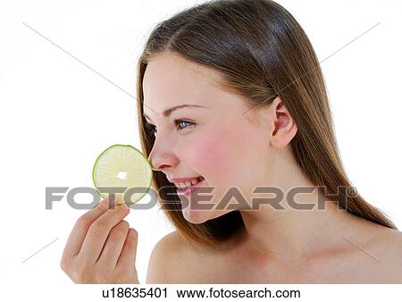 Stock Image - Close-up of a young woman holding a slice of lime. Fotosearch