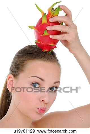 Stock Photo - Close-up of a young woman holding a pitaya fruit on her head. Fotosearch