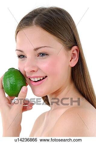 Stock Photograph - Close-up of a young woman holding a lime and smiling. Fotosearch