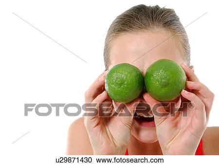 Stock Image - Close-up of a young woman holding two limes in front of her eyes. Fotosearch