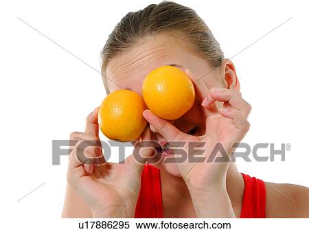 Stock Photography - Close-up of a young woman holding two oranges in front of her eyes. Fotosearch
