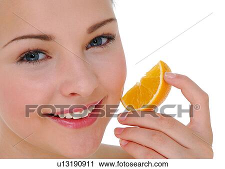 Portrait of a young woman holding a slice of orange View Large Photo Image Stock Image - Portrait of a young woman holding a slice of orange. Fotosearch