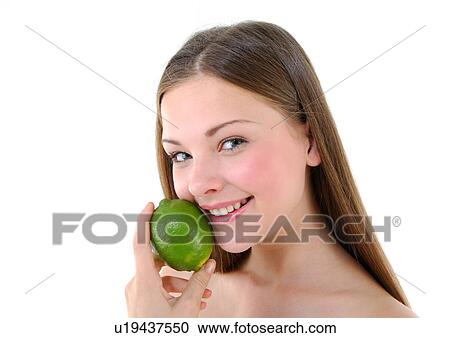 Stock Image - Portrait of a young woman holding a lime and smiling. Fotosearch
