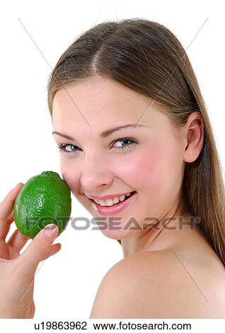 Stock Image - Portrait of a young woman holding a lime and smiling. Fotosearch