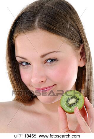 Stock Photography - Portrait of a young woman holding a half kiwi fruit. Fotosearch