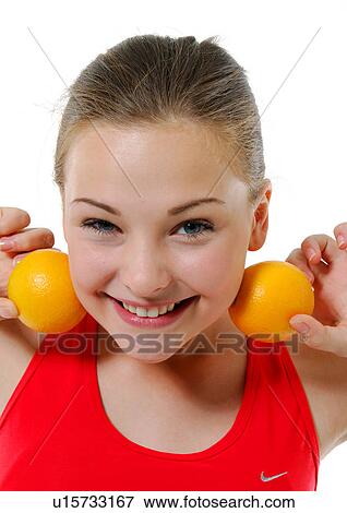Portrait of a young woman holding two oranges besides her two cheek and smiling View Large Photo Image Stock Photo - Portrait of a young woman holding two oranges besides her two cheek and smiling. Fotosearch