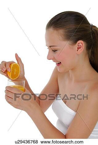 Stock Photo - Side profile of a young woman squeezing an orange. Fotosearch