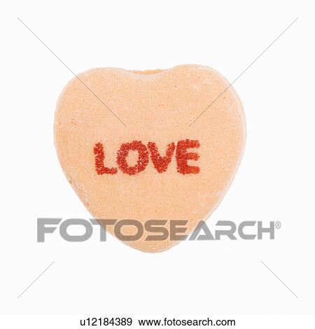 Stock Photo - Orange candy heart that reads love against white background.. Fotosearch