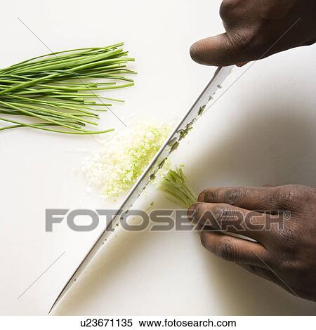 Stock Photography - African-American male hands using large kitchen knife to chop fresh chives.. Fotosearch