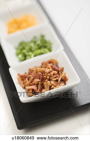 Stock Photo - Baked potato side dishes filled with cheese, scallion onions, sour cream, and bacon.. Fotosearch