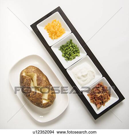 Baked potato sliced down the middle with several toppings. View Large Photo Image Picture - Baked potato sliced down the middle with several toppings.. Fotosearch