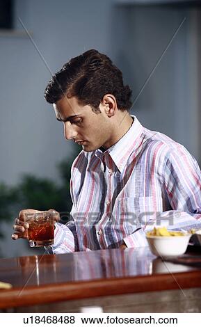 Stock Photo - A man in a bar looking at his drink. Fotosearch
