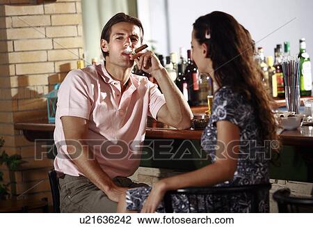 Couple in a bar, man smoking cigar View Large Photo Image Stock Image - Couple in a bar, man smoking cigar. Fotosearch