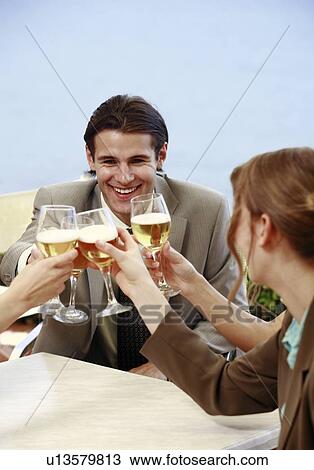 Stock Image - Office workers toasting with beer in outdoor cafe. Fotosearch