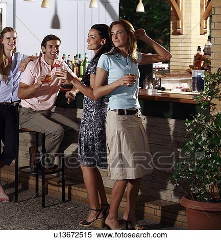 Stock Photography - Three women and a man in a bar. Fotosearch