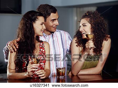 Two women and man in a bar View Large Photo Image Stock Image - Two women and man in a bar. Fotosearch