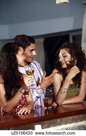 Two women and man in a bar View Large Photo Image Stock Image - Two women and man in a bar. Fotosearch