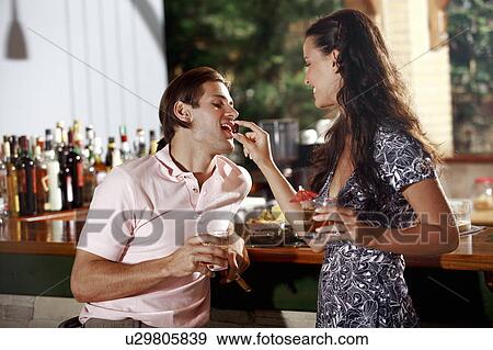 Woman feeding man in a bar View Large Photo Image Stock Photo - Woman feeding man in a bar. Fotosearch