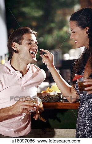 Woman feeding man in a bar View Large Photo Image Stock Photograph - Woman feeding man in a bar. Fotosearch