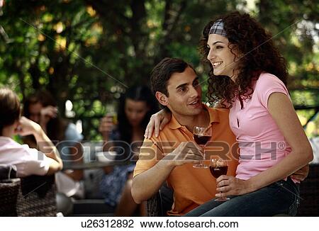 Stock Image - Woman sitting on man's lap in outdoor cafe. Fotosearch