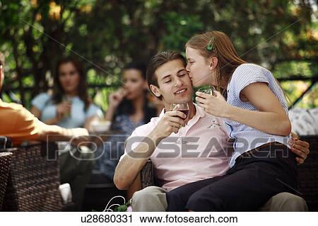Stock Image - Woman sitting on man's lap in outdoor cafe. Fotosearch