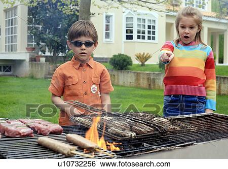 Boy and girl standing near a barbecue View Large Photo Image Stock Photograph - Boy and girl standing near a barbecue. Fotosearch