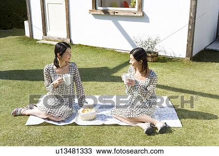 Twin sisters sitting on sheet in garden, tea time, front view View Large Photo Image Stock Image - Twin sisters sitting on sheet in garden, tea time, front view. Fotosearch