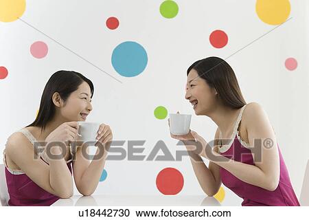 Two Young Twin Sisters Drinking, Sitting at Table, Smiling, Side View View Large Photo Image Stock Image - Two Young Twin Sisters Drinking, Sitting at Table, Smiling, Side View. Fotosearch