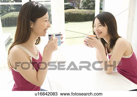 Two Young Twin Sisters Sitting at Table Drinking, Smiling, Side View View Large Photo Image Stock Image - Two Young Twin Sisters Sitting at Table Drinking, Smiling, Side View. Fotosearch