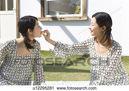 Woman feeding her sister, twin sisters, smiling, side view View Large Photo Image Stock Image - Woman feeding her sister, twin sisters, smiling, side view. Fotosearch