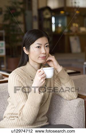Woman sitting and holding a cup in the lobby, front view, Japan View Large Photo Image Stock Image - Woman sitting and holding a cup in the lobby, front view, Japan. Fotosearch