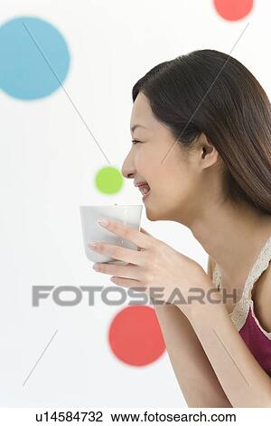 Young Woman Drinking, Holding a Cup, Smiling, Side View View Large Photo Image Stock Image - Young Woman Drinking, Holding a Cup, Smiling, Side View. Fotosearch