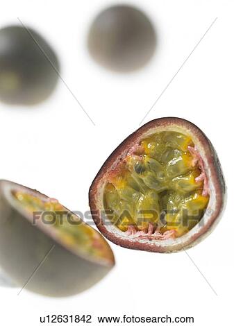 Stock Image - One Passion Fruit cut in half with two passion fruits in the background. Fotosearch