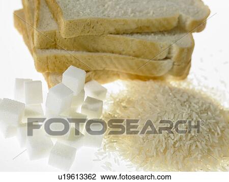 Stock Image - White bread slices beside piles of sugar and rice. Fotosearch