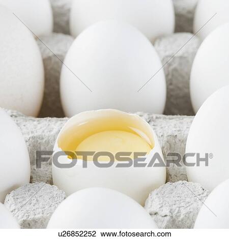 Stock Image - Close-up of a broken egg in an egg carton. Fotosearch