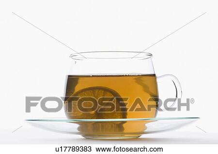 Stock Image - Slice of lemon in a cup of herbal tea. Fotosearch