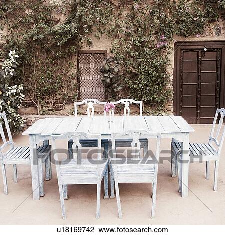 Stock Image - Dining table and chairs out side a house. Fotosearch