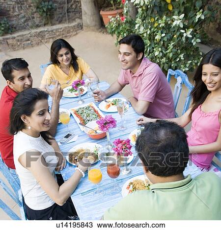 Stock Image - High angle view of a mid adult couple with their friends having food. Fotosearch