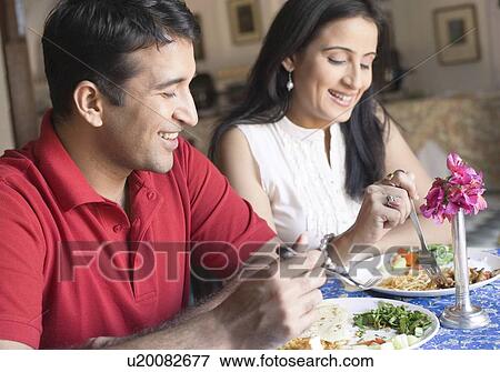 Stock Photo - Mid adult couple having food in a restaurant and smiling. Fotosearch