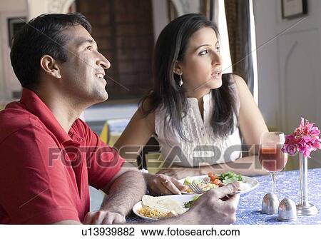 Stock Image - Mid adult couple sitting in a restaurant and smiling. Fotosearch