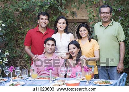Stock Image - Portrait of a group of people at a dining table and smiling. Fotosearch