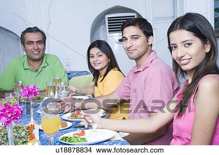 Picture - Portrait of a mid adult couple and a young couple sitting at a dining table. Fotosearch