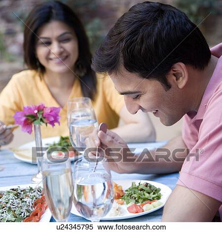 Stock Photography - Young man with a mid adult woman having food. Fotosearch