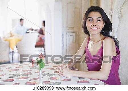 Young woman sitting in a restaurant and smiling View Large Photo Image Stock Photo - Young woman sitting in a restaurant and smiling. Fotosearch
