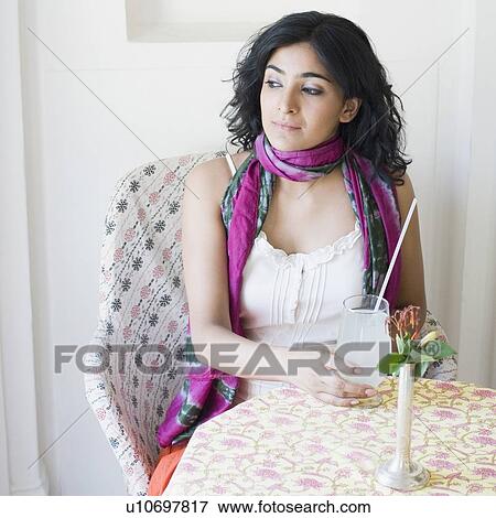 Young woman sitting in a restaurant and holding a glass of lemon juice View Large Photo Image Stock Photo - Young woman sitting in a restaurant and holding a glass of lemon juice. Fotosearch