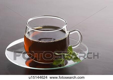 Picture - Close-up of a cup of herbal tea with mint leaf in a saucer. Fotosearch