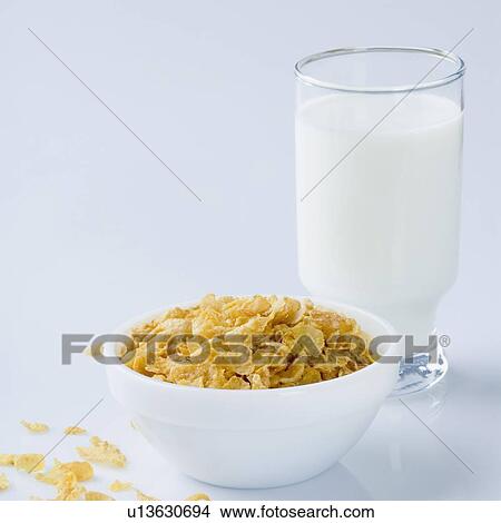 Picture - Close-up of a glass of milk with a bowl of corn flakes. Fotosearch