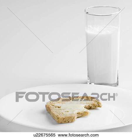 Stock Photography - Close-up of a glass of milk with brown bread in a plate. Fotosearch